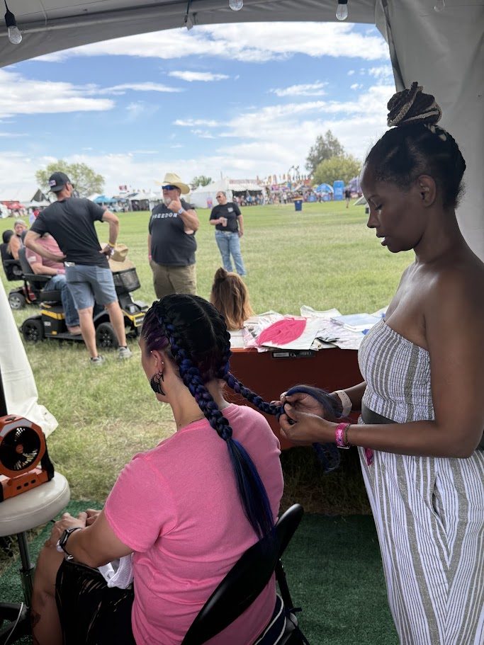 Stylist braiding blue Dutch braids at Country Thunder AZ
