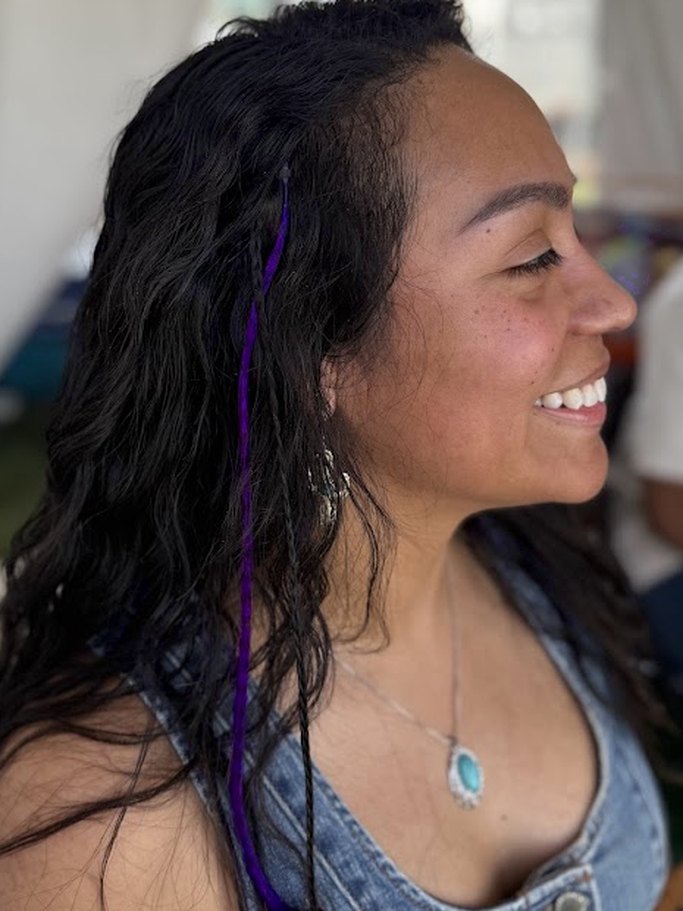 Smiling festival guest with a purple color braid